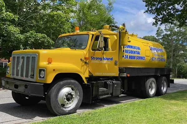 A yellow truck is parked on the side of the road for cesspool maintenance.