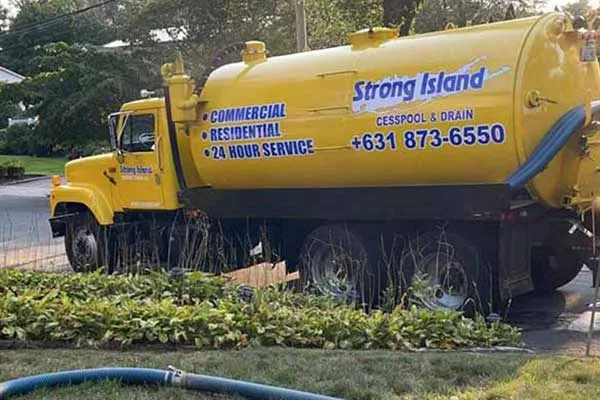 A yellow garbage truck is parked in front of a house, ready for drain cleaning.